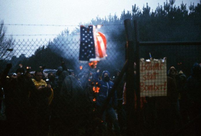 Воислав Шешел запали запали знамената на ЕС и НАТО. Снимка: Общомеди