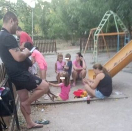 Родителите стоят в пясъчника на детската площадка