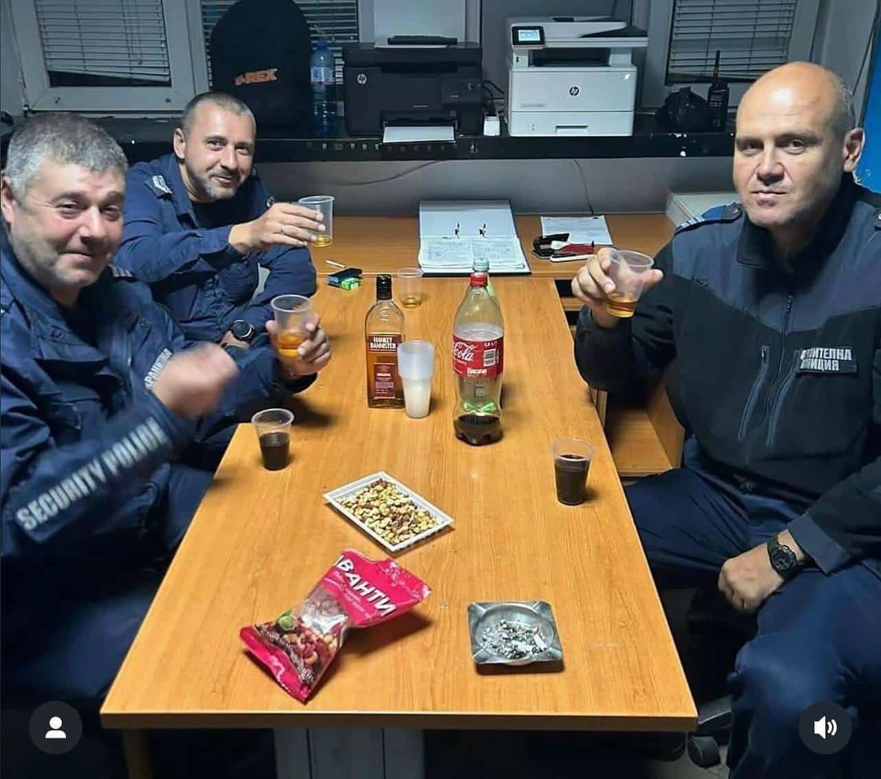 Снимка на трима мъже с полицейски униформи които консумират алкохол