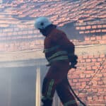 Пожарникар гаси пожар на покрив на къща