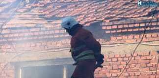 Пожарникар гаси пожар на покрив на къща