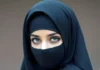 Снимката изобразява жена с бурка, гледаща към камерата